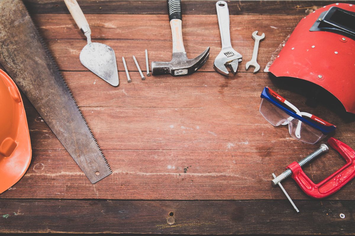 Workbench with hammer, wrench and repair tools laid out on timber