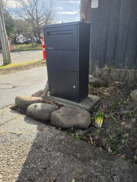 New black parcel mailbox installed on a rock-bordered plinth in Christchurch